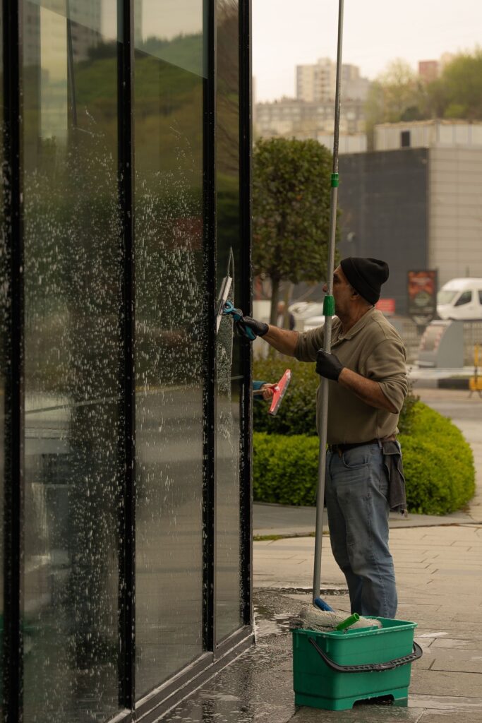 Professional cleaning a glass facade with a squeegee